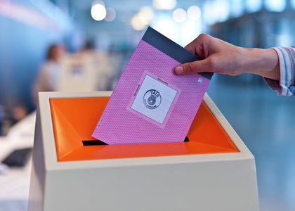 En person som putter stemmeseddel i valgboks - Klikk for stort bilde